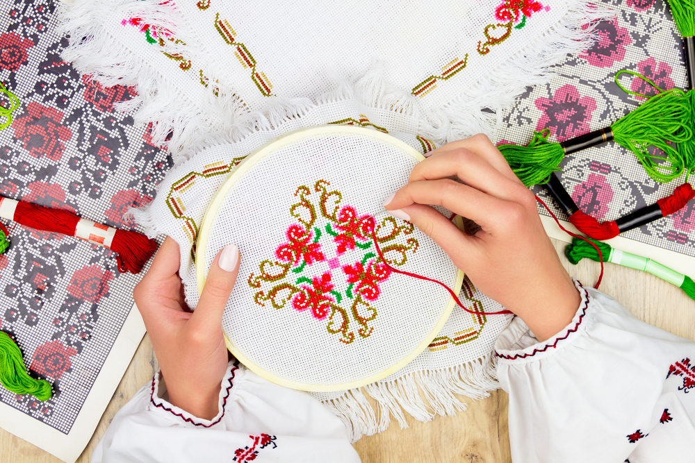 Photo of hands embroidering a motif in a counted thread technique.