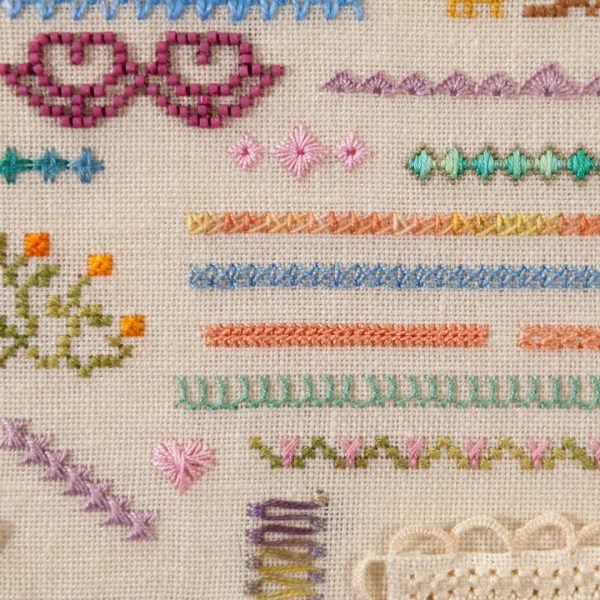 Photo of an embroidery with a variety of motifs and rows stitched on evenweave fabric.