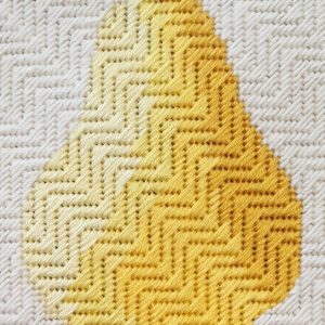 A photo of an embroidered, textured pear on a textured background. The pear is stitched in shades of yellow to give it a rounded appearance.