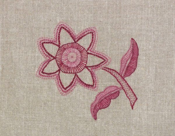 photo of a pink wool flower embroidered with a variety of textured embroidery stitches on linen fabric