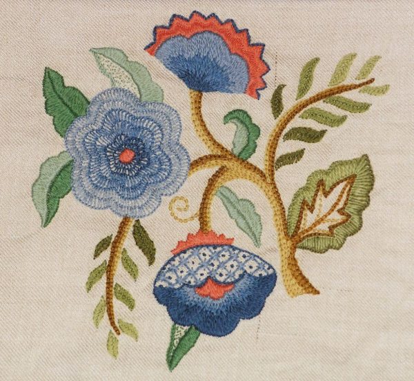 photo of a group of wool flowers and leaves embroidered with a variety of textured embroidery stitches on linen fabric