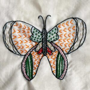 Photo of an embroidered butterfly that uses different stcitches to fill shapes on the wings and creates texture.