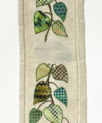 Photo of a long narrow piece of embroidery with a beanstalk going through clouds up to a castle. The leaves are embroidered with different techniques that cause each leaf to have a different texture.