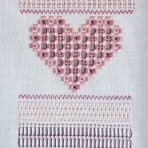 photo of a tall narrow sampler with bands of a variety of stitches, many forming heart shapes