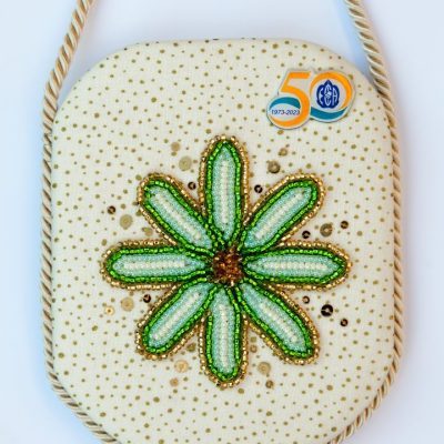 photo of a pendant with bead embroidered flower and a 50th anniversary pin