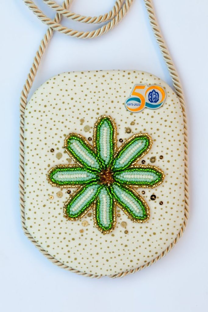 photo of a pendant with bead embroidered flower and a 50th anniversary pin