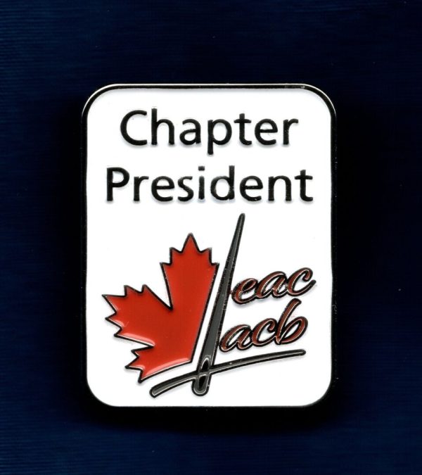 Photo of an enameled pin with a white background. The words Chapter President are at the top. There is a partial red maple leaf on the left. A gray sewing needle is dividing the maple leaf from the red letters "EAC" and "ACB" that are stacked on the right. A line representing a wide gray thread is under all of the elements. It looks like the thread is through the eye of the needle.