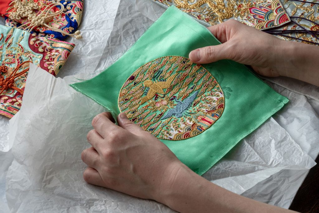 Photo of hands holding a piece of embroidery created in a traditional Korean style.