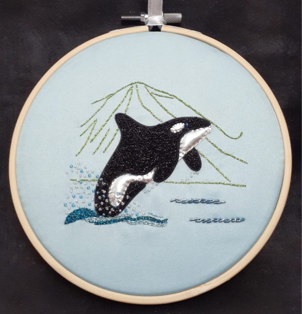 Photo of an embroidered orca rising out of the sea.