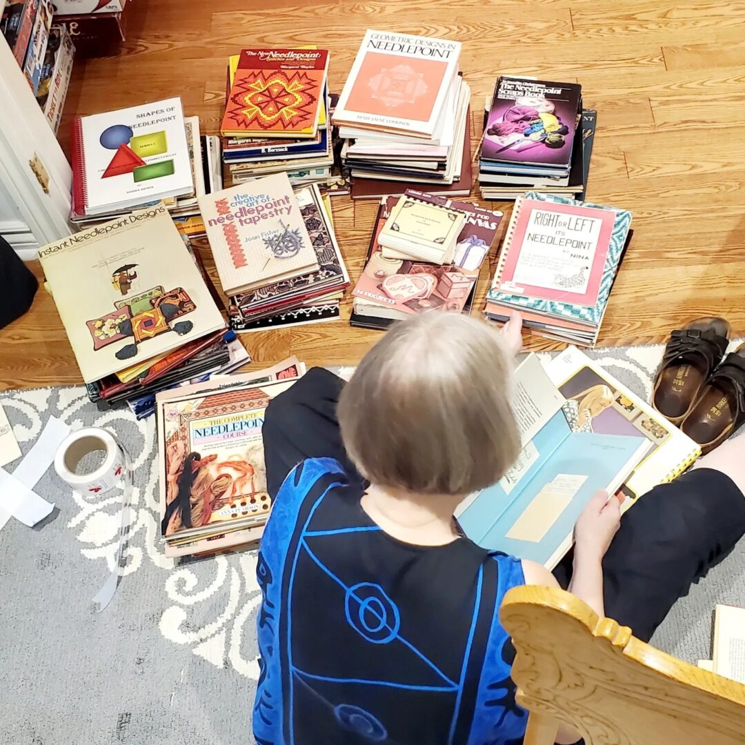 photo of a person sitting on the floor with short stacks of books piled around them