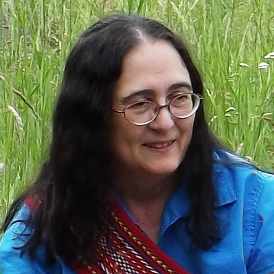 Photo of a woman with long dark hair and a colourful woven sash over her right shoulder.