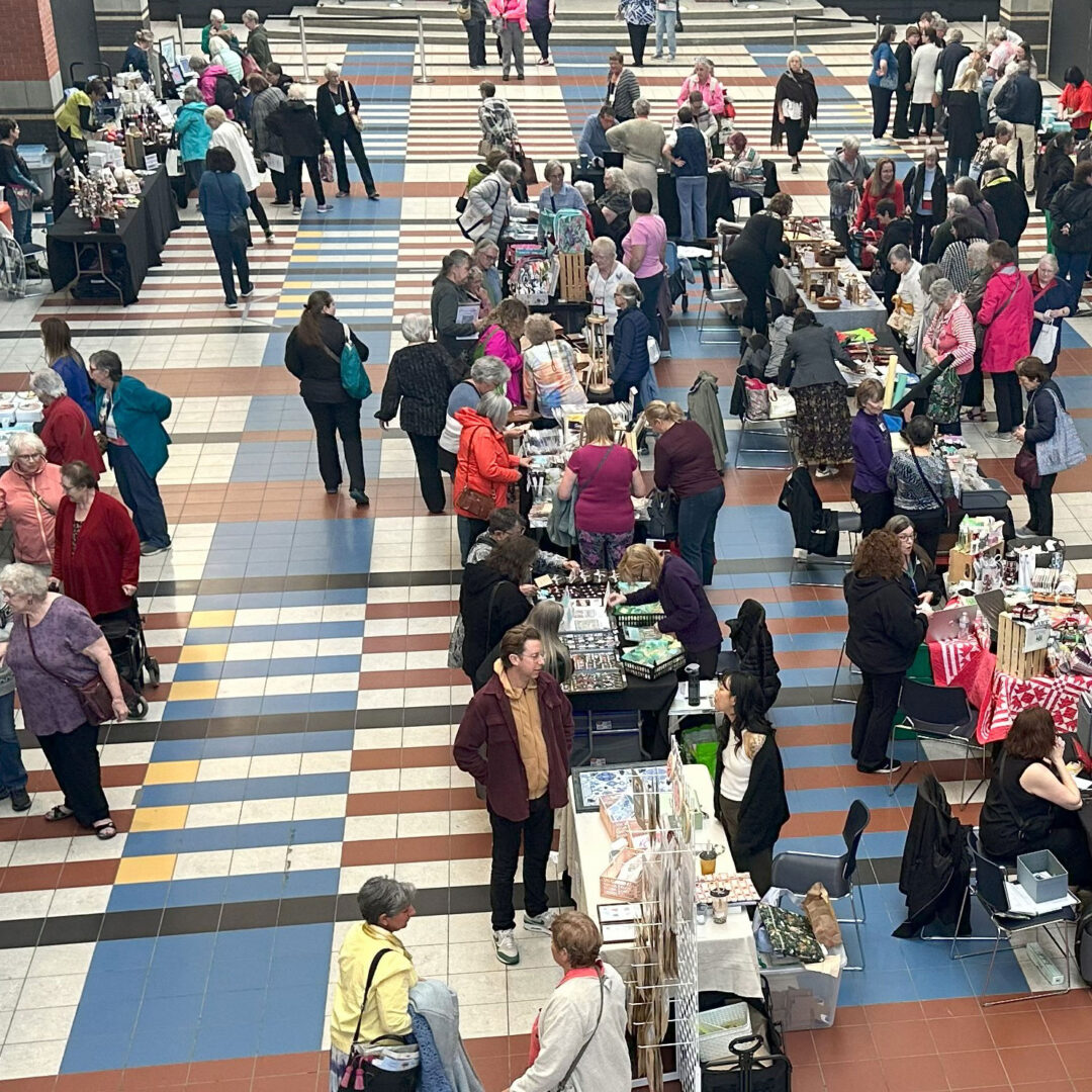 Large group of people gathering around displays and talking.