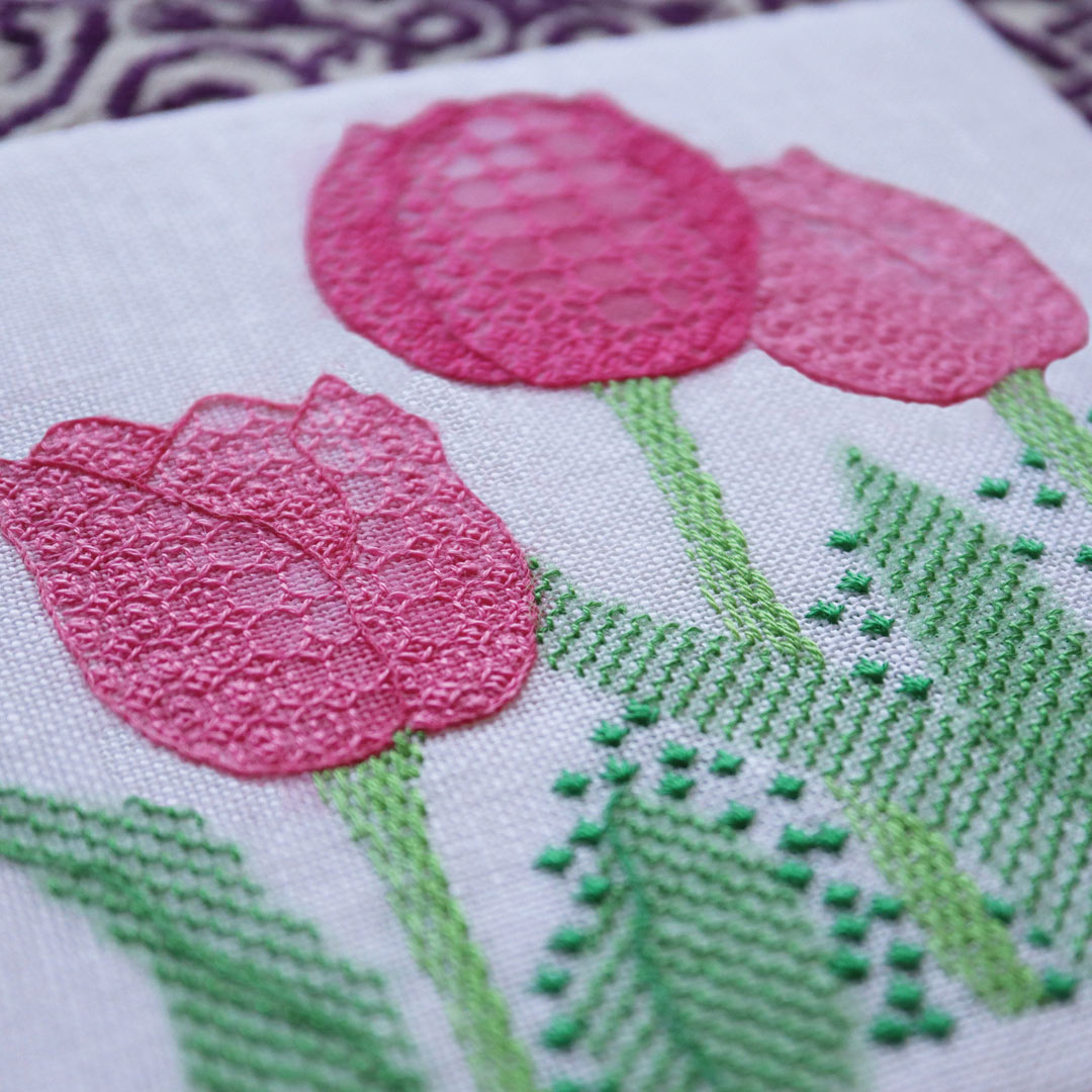 photo of embroidered pink tulips and green leaves with the density of the stitches making some areas appear darker or lighter.