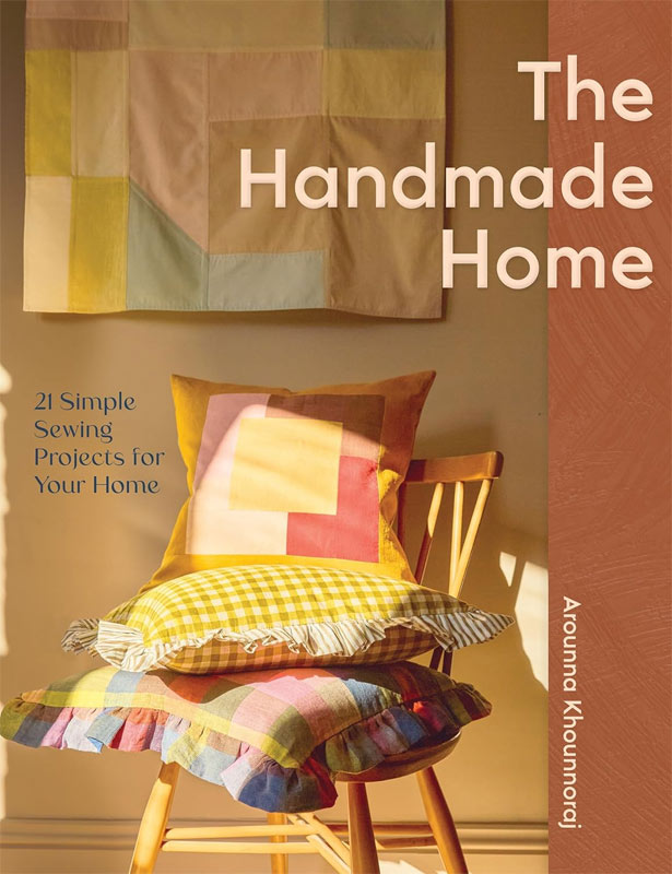 A photo of the cover of a book showing a fabric wall hanging behind a wooden chair with three cushions stacked on it.