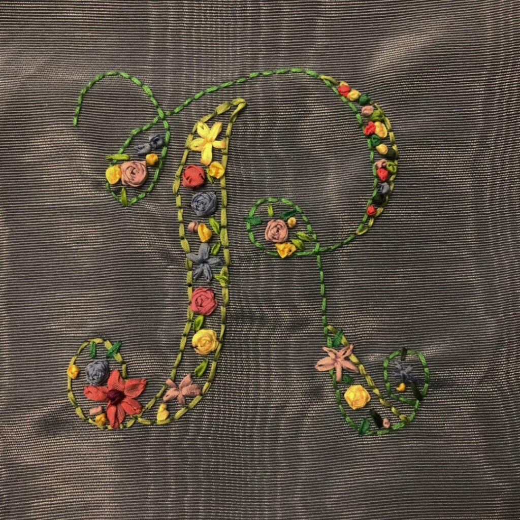 Photo of an "R" stitched with ribbon embroidery.