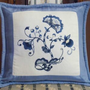 Photo of a cushion embroidered with stylized flowers in various shades of blue.