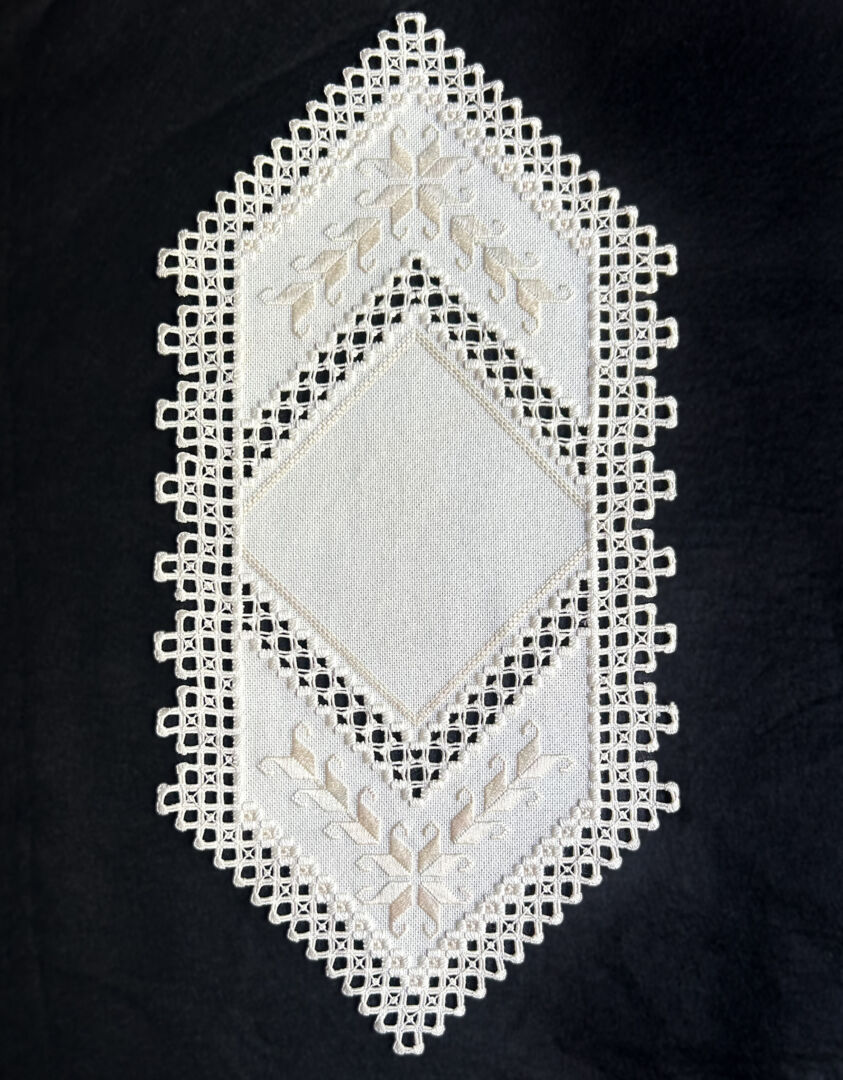 White geometric-shaped Hardanger table runner with Smyrna stitches, satin stitches and lacy buttonhole edging.