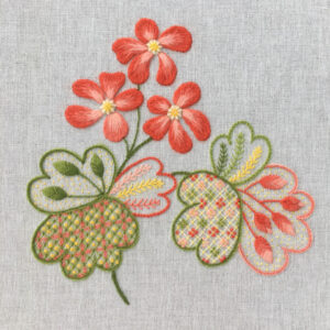 Crewelwork flowers and leaves. Flowers are 2 shades of coral while the leavess...of various shapes and stitches...are green, peach and yellow. Various stitches include satin, stem, daisy and French knots.