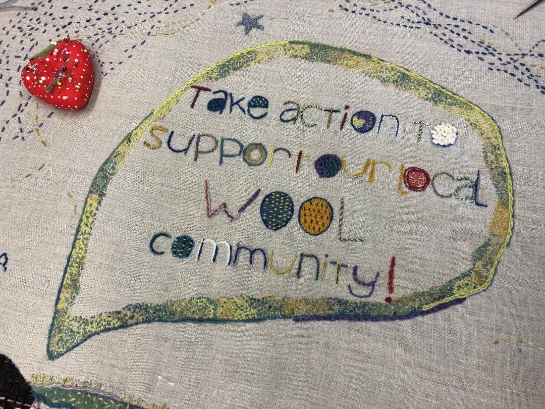 Part of Kathleen's tapestry. This reads "Take action to support our local wool community" and is stitched in various types and colours of yarn.